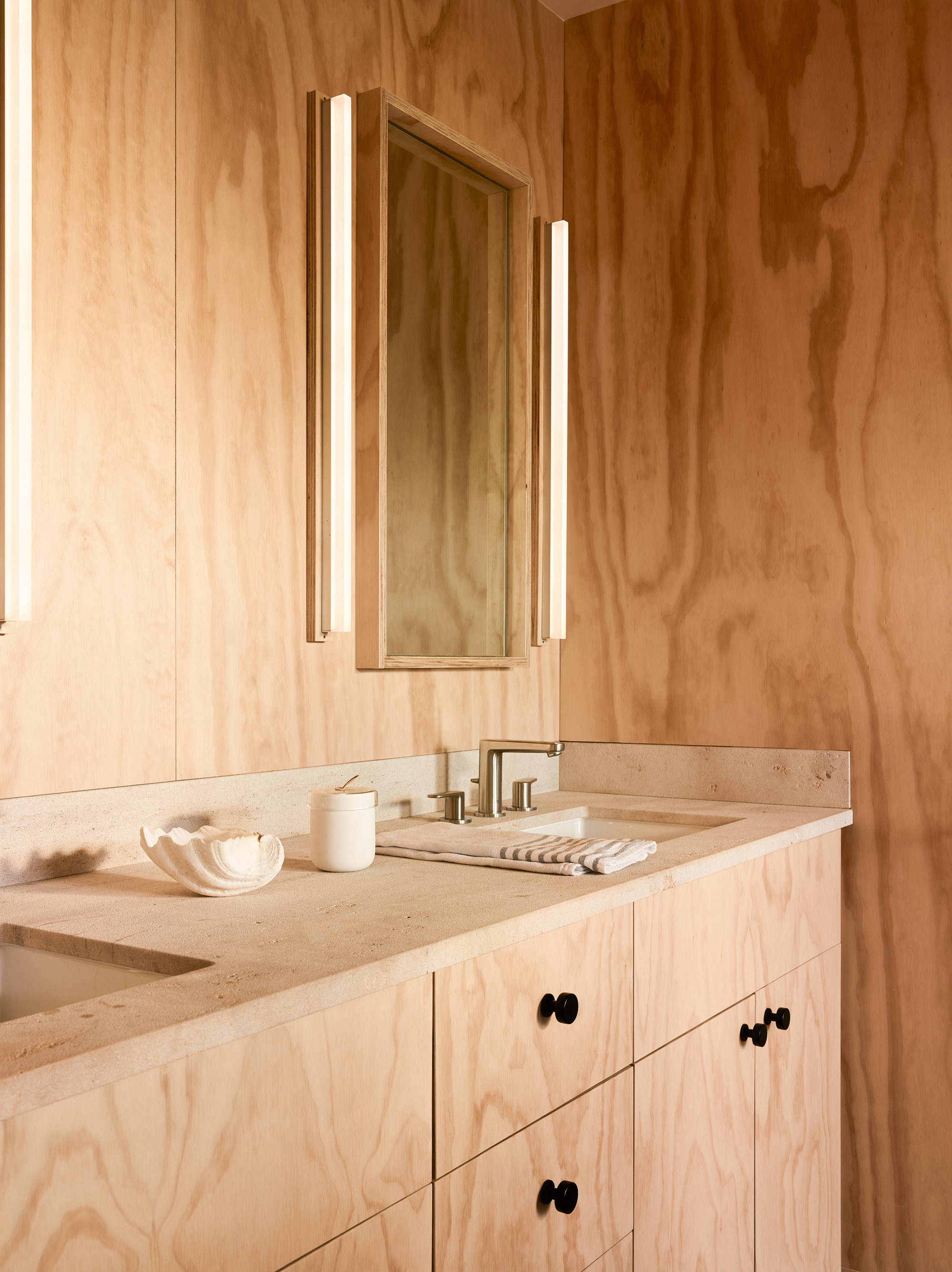 a plywood bathroom with a mirror with lighting