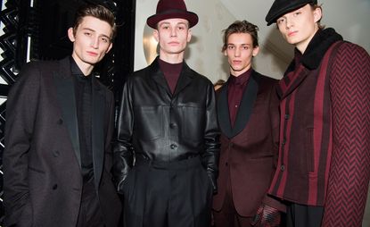 Four models in black and maroon clothing looking directly at the camera