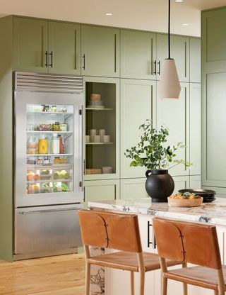 Chef's kitchen with green cabinets and fridge