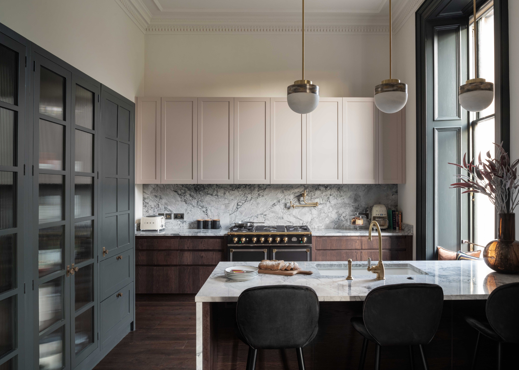 a grey kitchen with off-white walls, wooden cabinets, marble counters and a range over.