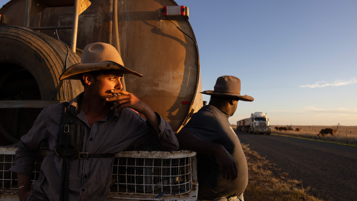Drover smoking cigarette looking towards sunset. 