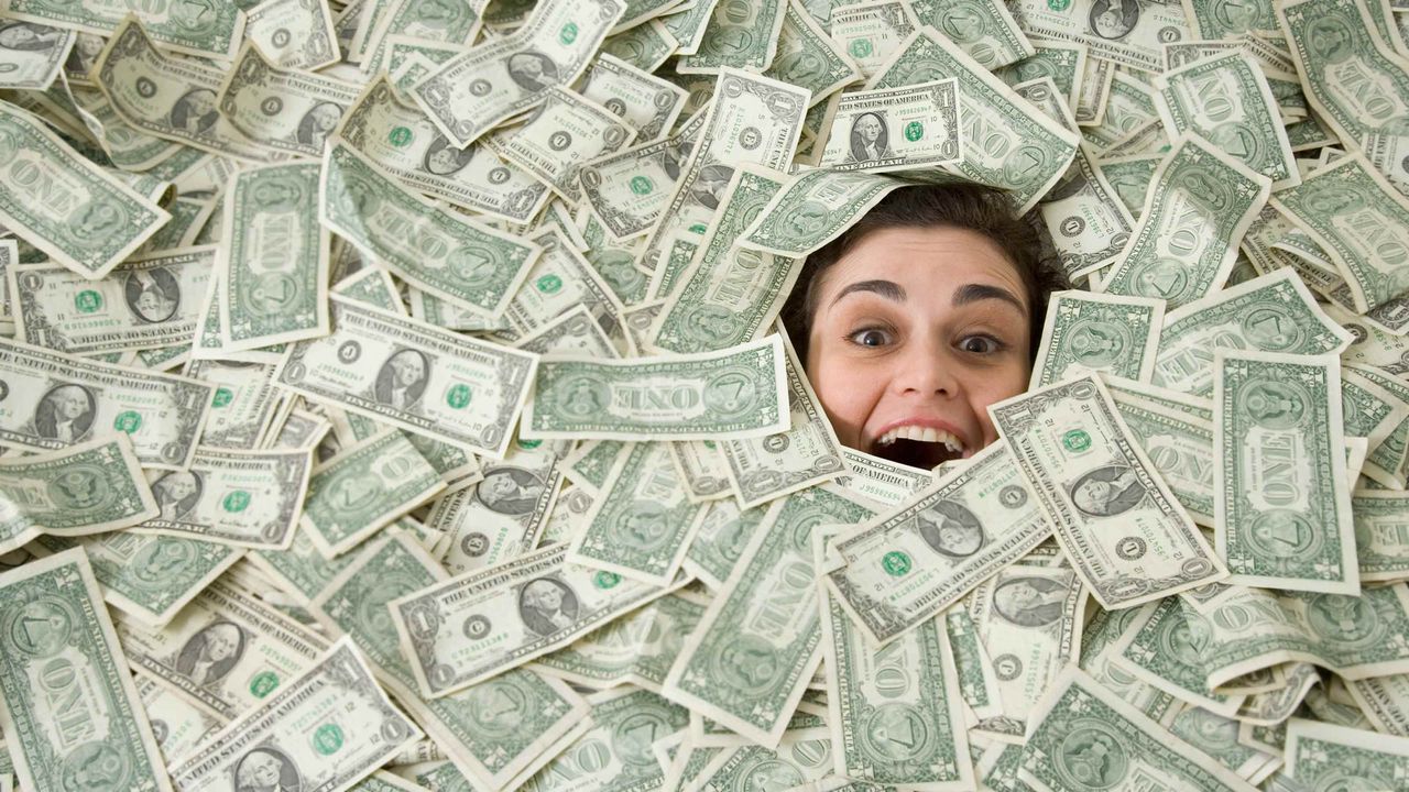 A woman&amp;#039;s face peeks out from beneath a pile of money.