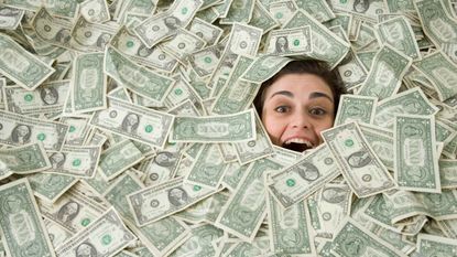 A woman's face peeks out from beneath a pile of money.