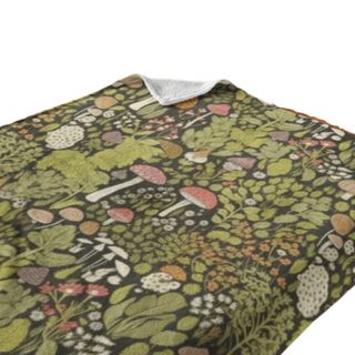 A green throw with mushroom and leaf illustrations