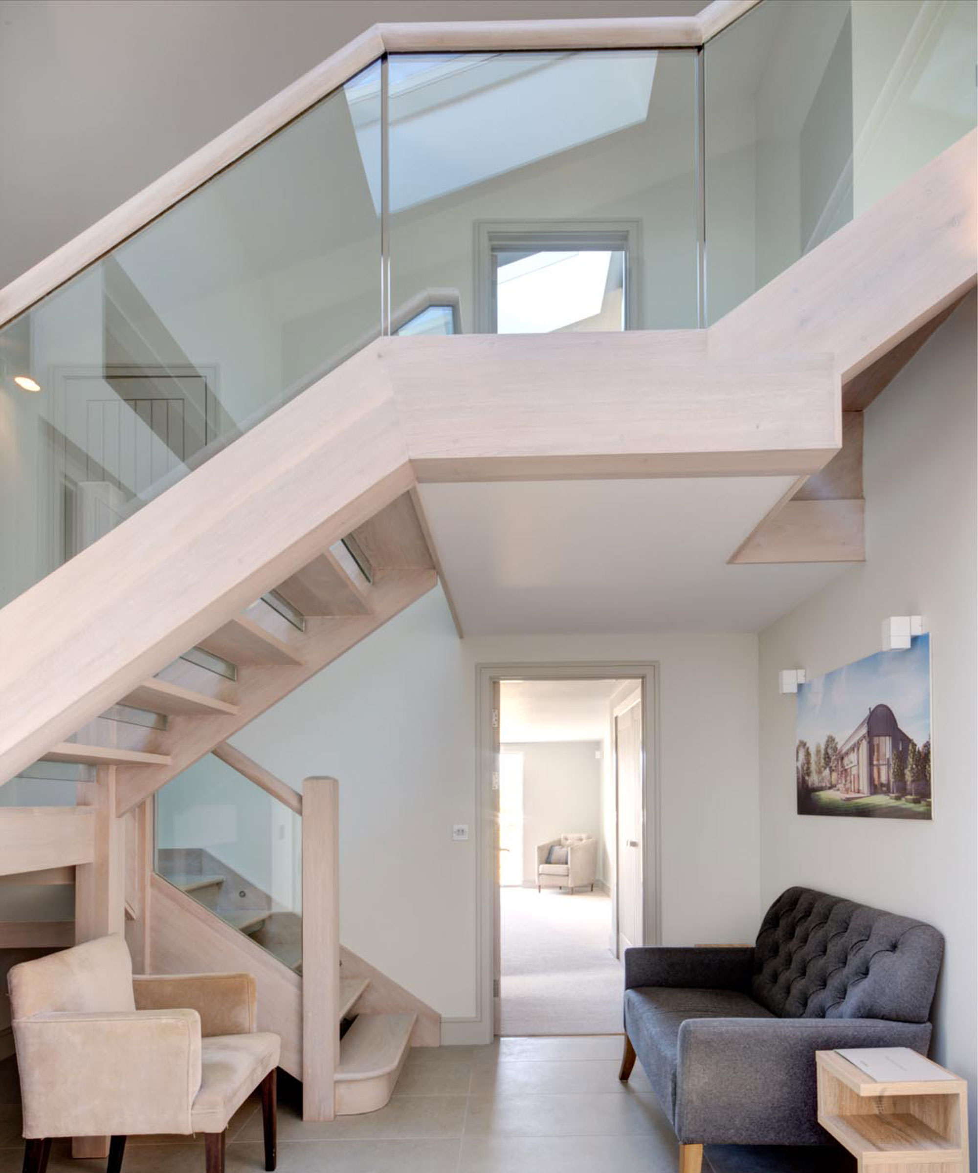 double height hallway with light wood staircase within a Dutch barn conversion