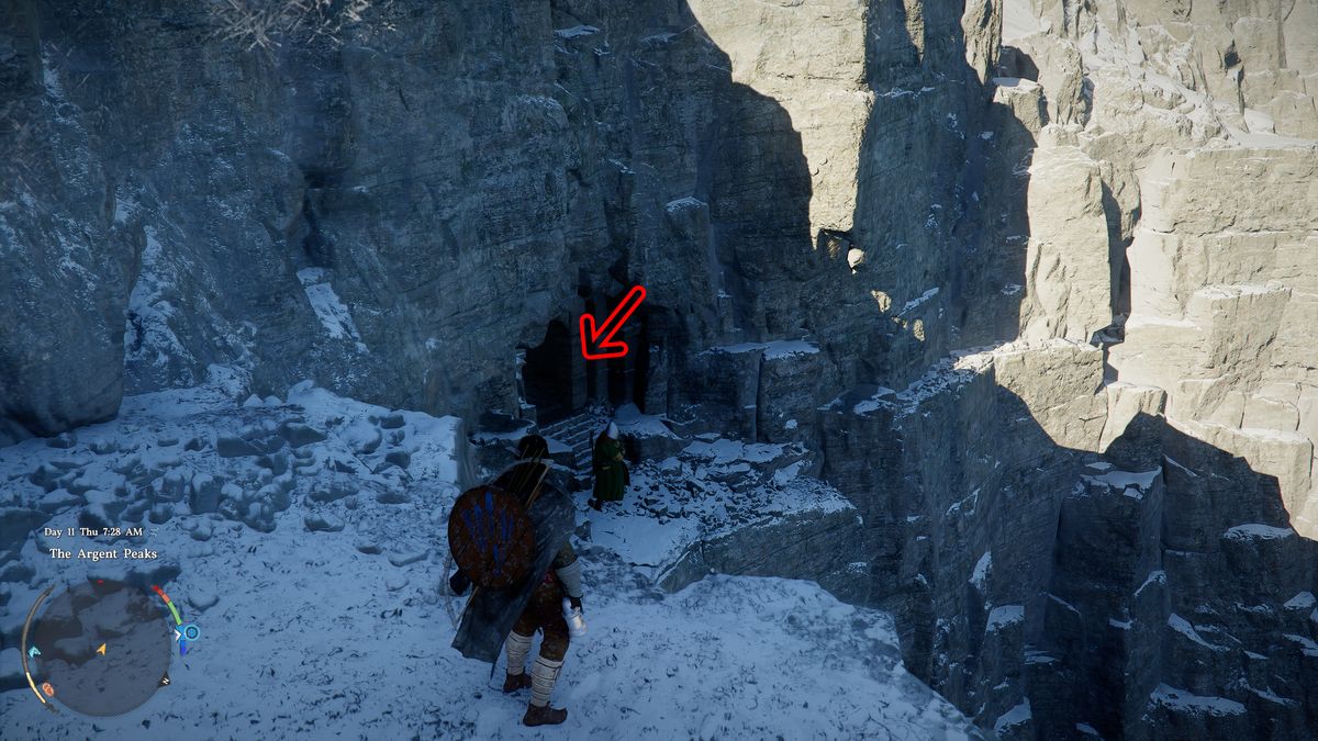 Crimson Desert Soul Spear: Kliff standing next to a ledge overlooking a cave entrance in a snowy cliff side, with a red arrow pointing inside.
