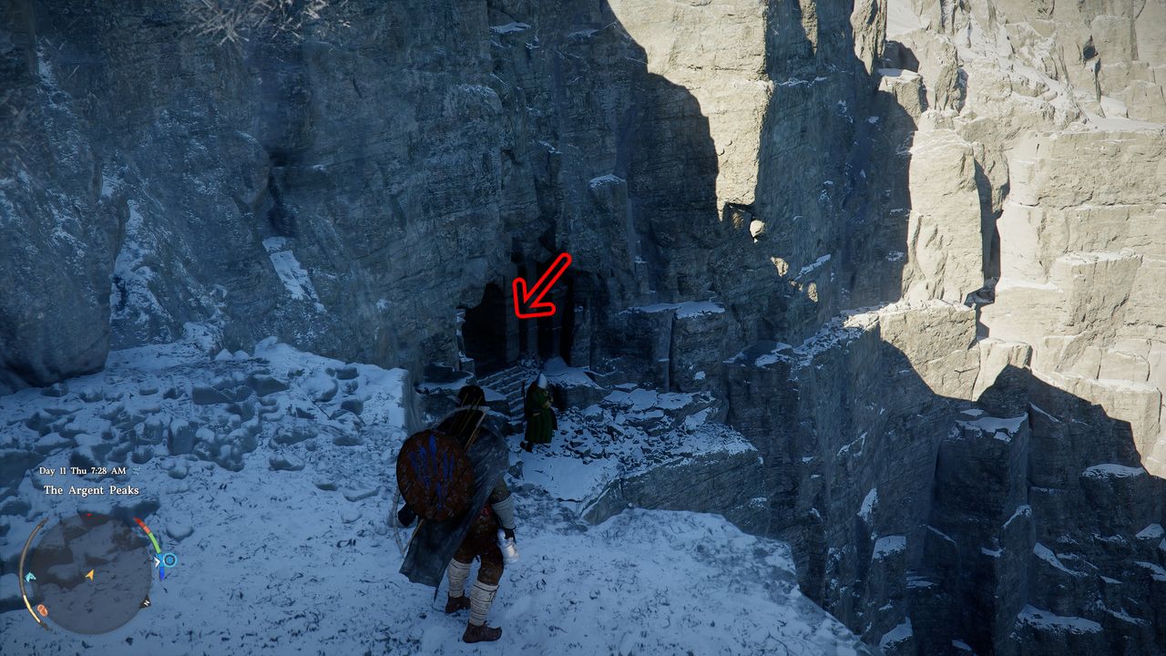 Crimson Desert Soul Spear: Kliff standing next to a ledge overlooking a cave entrance in a snowy cliff side, with a red arrow pointing inside.
