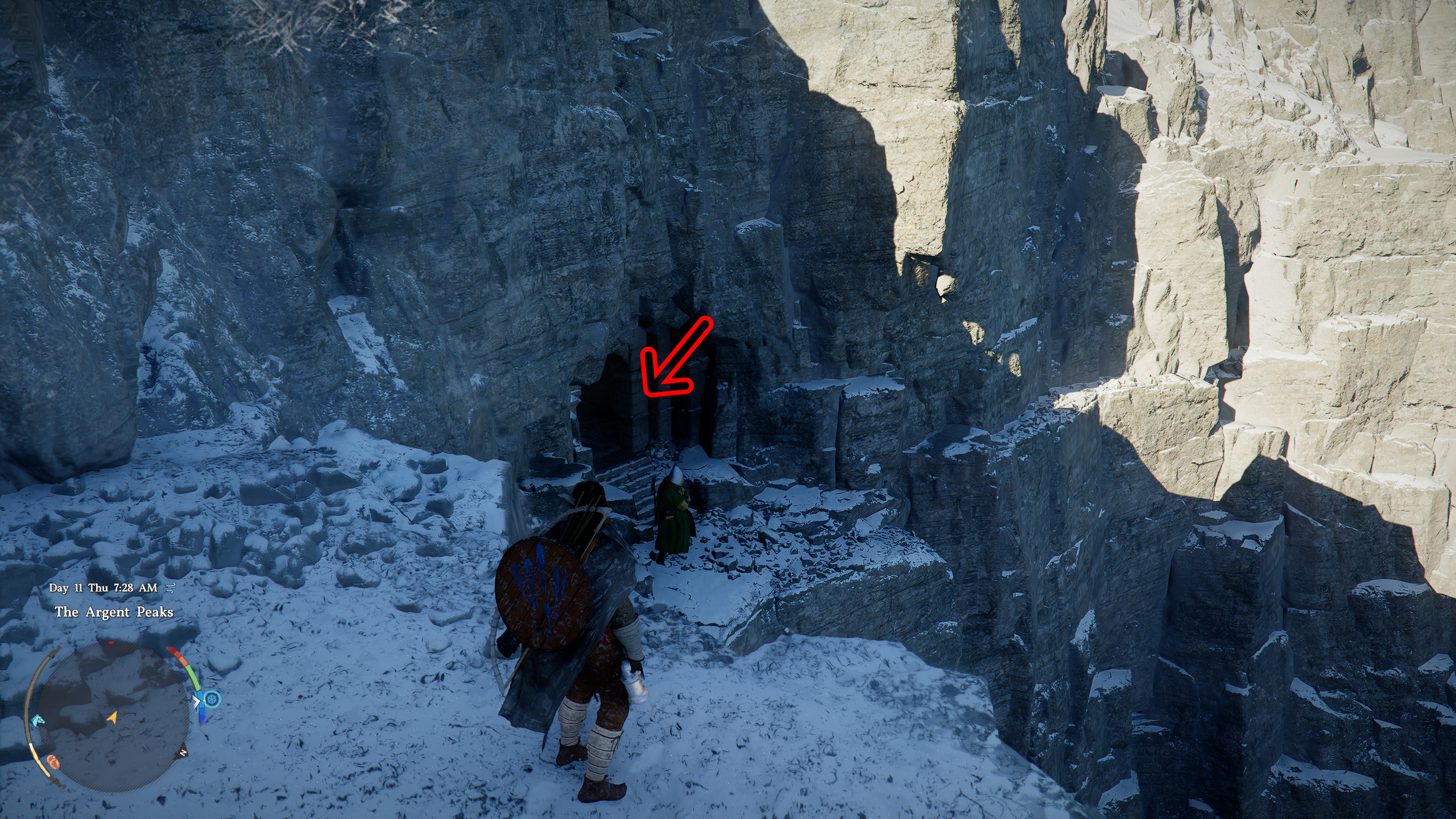  Kliff standing next to a ledge overlooking a cave entrance in a snowy cliff side, with a red arrow pointing inside.