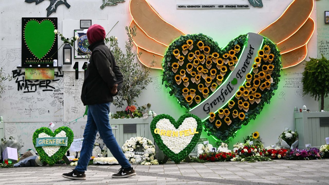 A man walks past floral tributes to Grenfell victims