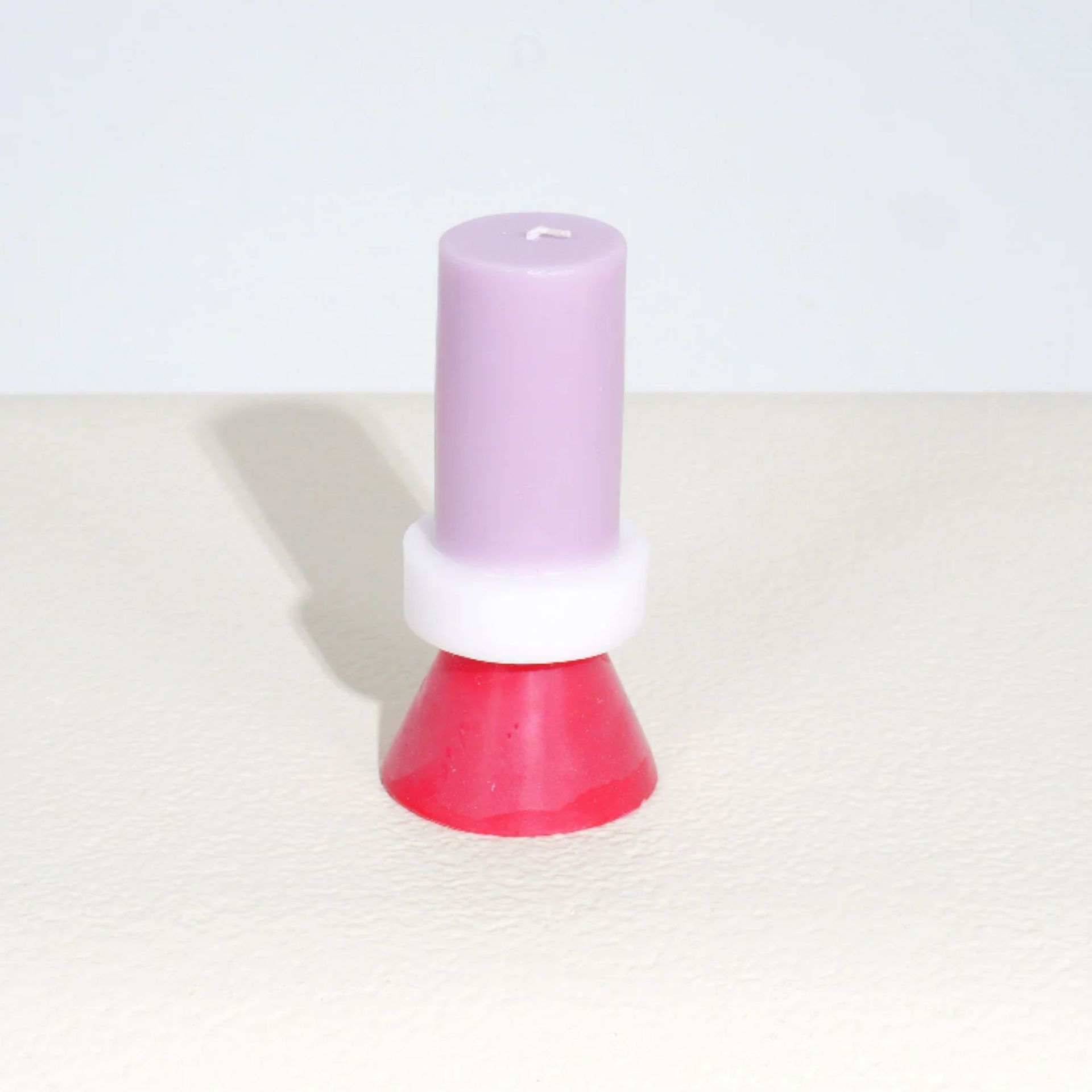 Sebuah lilin merah muda, putih dan ungu