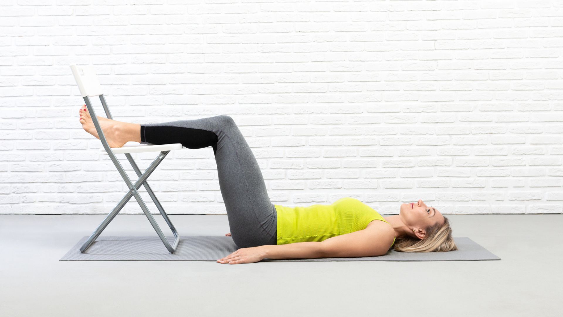 woman on yoga mat with feet on chair