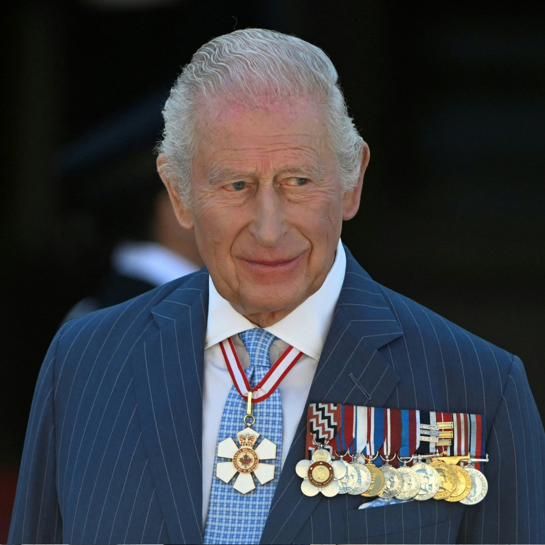 King Charles wearing a blue striped suit with medals