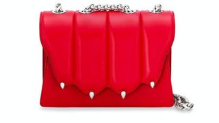 A red handbag with silver colored chain strap.