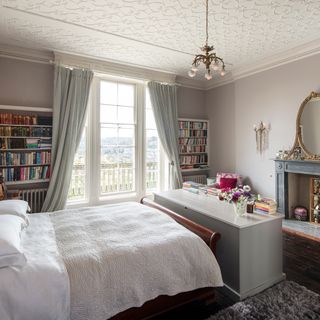 bedroom with white bed and book shelves on wall