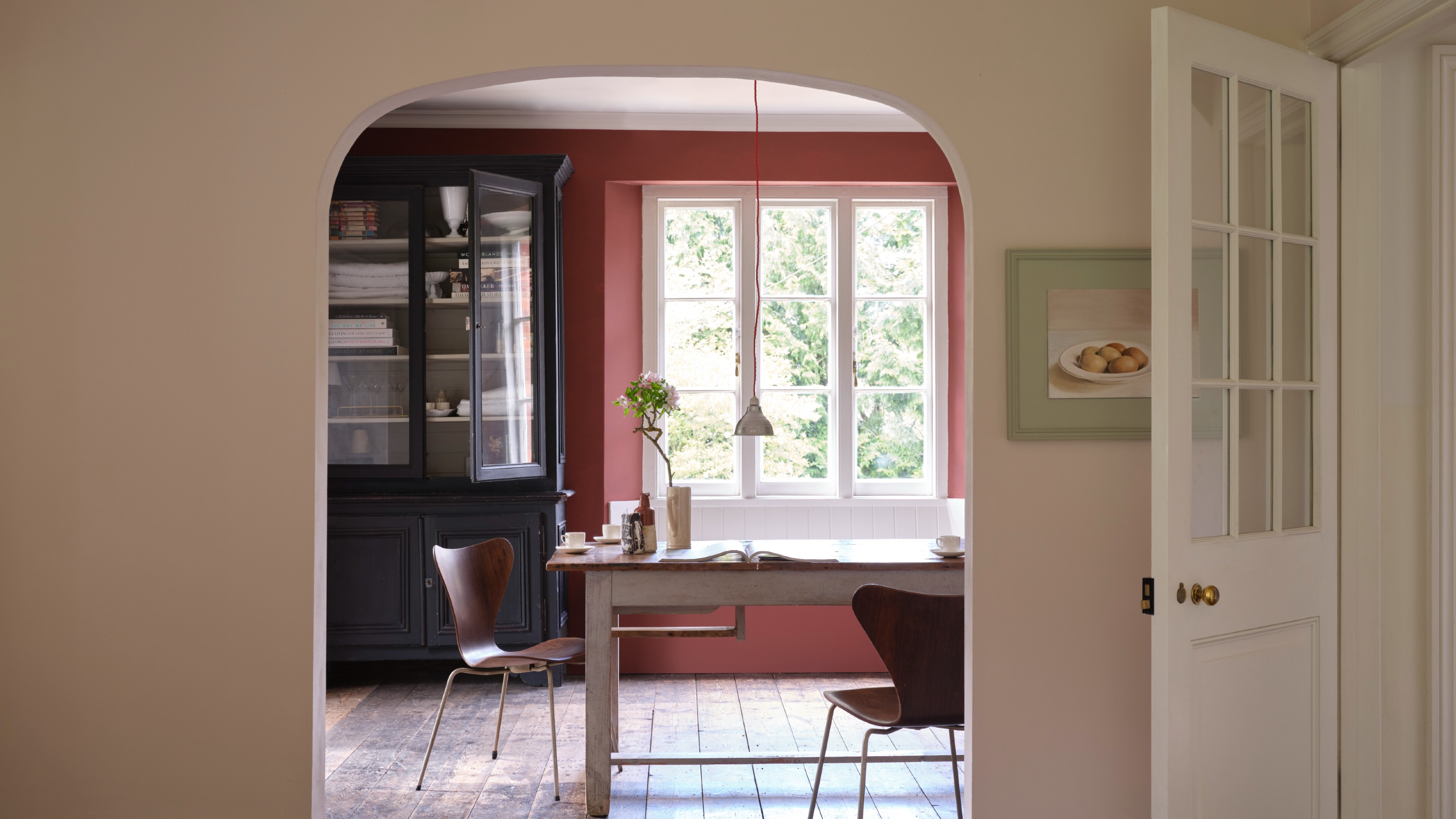 An arched entrance into a rustic dining room with the surrounding wall painted in Scallop 