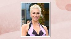 Portrait of Hannah Waddingham smiling with her blonde hair in an updo, wearing a purple printed halterneck dress and a blush pink lipstick