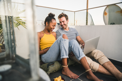 Couple sitting on balcony, wondering if it is safe to book a holiday in 2021
