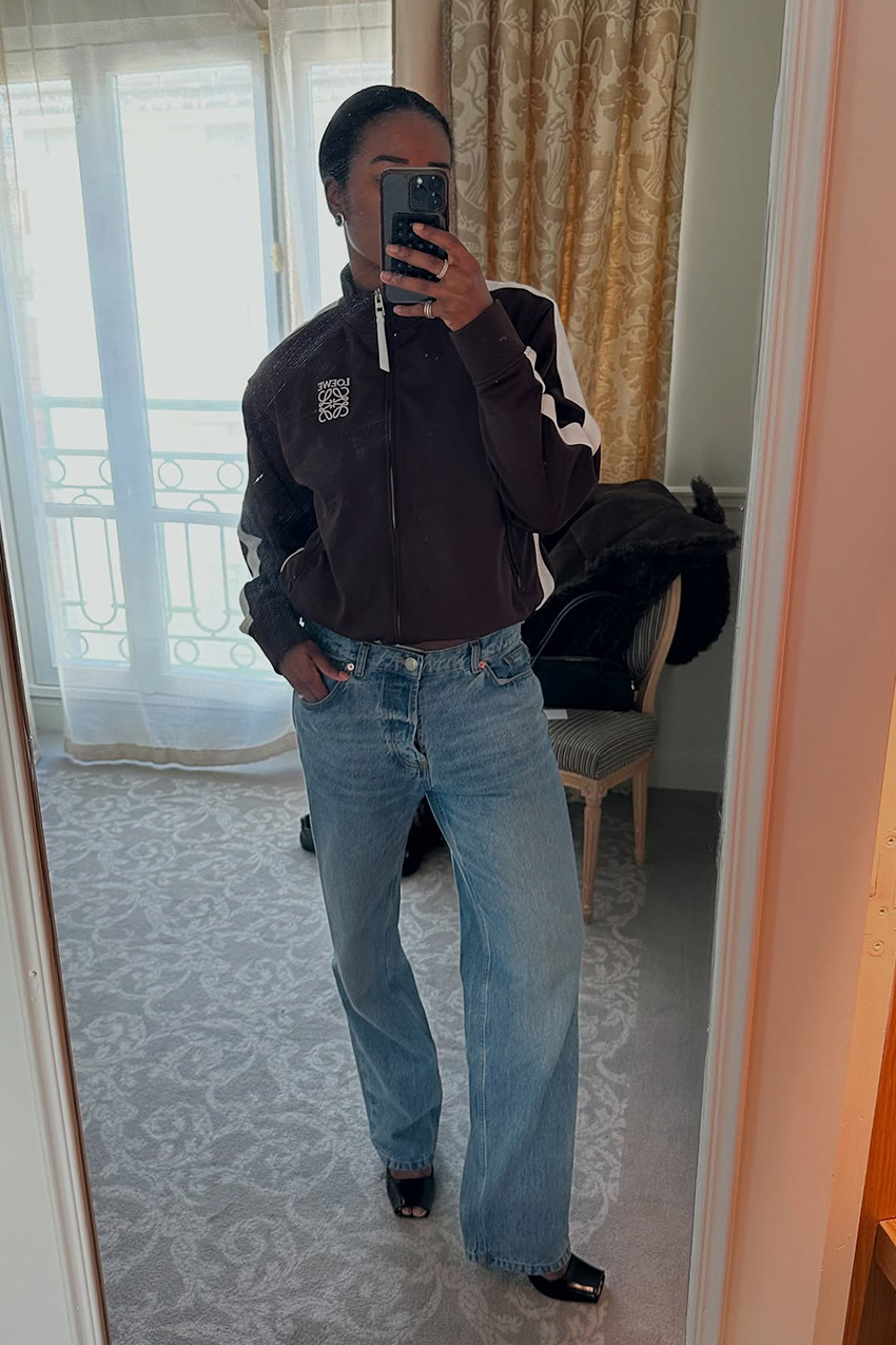 a woman wearing a brown Loewe track jacket, low-rise jeans, and peep-toe pumps