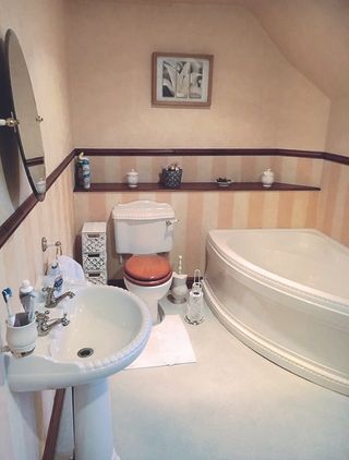 Before pic of bathroom with striped peach and white wallpaper, white sanitaryware and white floor