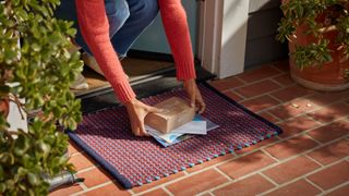 A woman collects an HP Instant Ink package from her front door