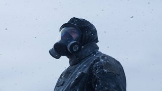 A man wears a gas mask while it's snowing