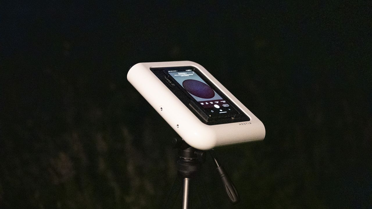 Vaonis Hestia smart telescope on a tripod pointing up at the night sky with a Google Pixel phone attached