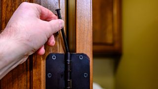 A hand removing a pin from a door hinge