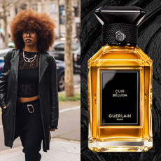 A woman with a coily afro blowout wearing and black top and pants, paired with a black leather jacket. She is flanked by two bottles of perfume.