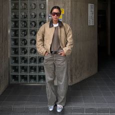 a woman wearing a contrast collar jacket, gray barrel jeans, and silver flats