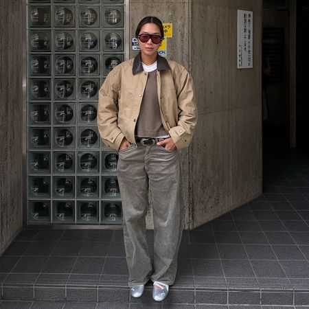 a woman wearing a contrast collar jacket, gray barrel jeans, and silver flats