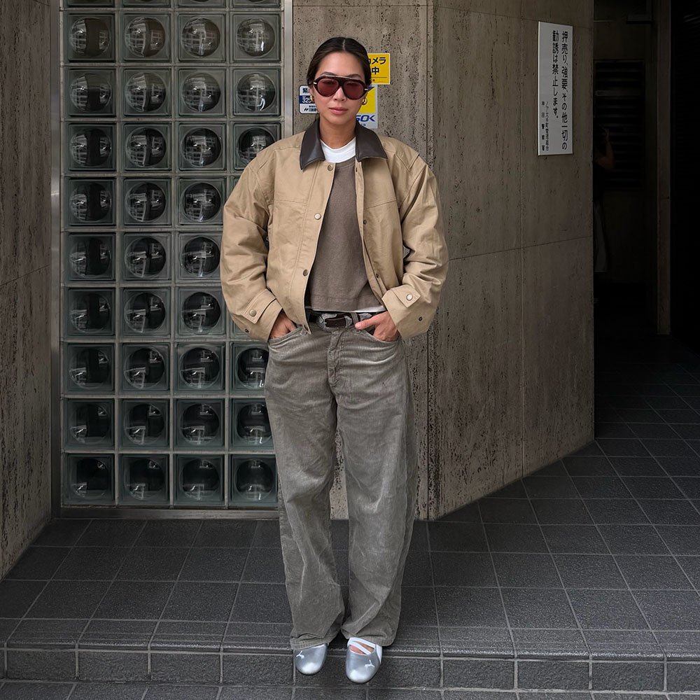 a woman wearing a contrast collar jacket, gray barrel jeans, and silver flats