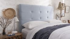 White bedroom with blue upholstered bed with white bedding to support expert guidance to ask do cooling mattresses work