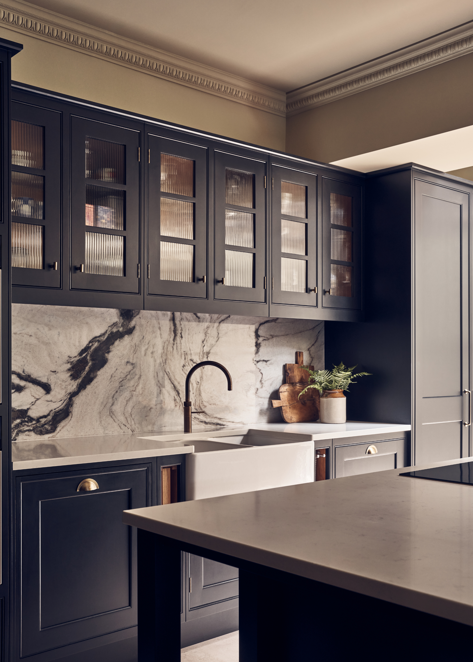 glass fronted dark blue cabinetry with a veined marble backsplash in a modern kitchen