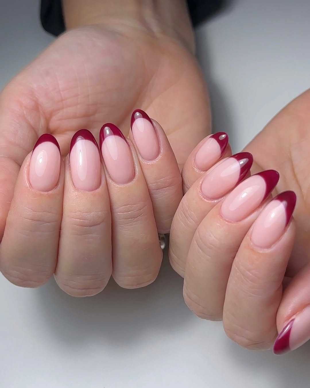 a person wearing a french manicure with dark red tips