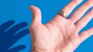 A close up of the Amazfit Helio Ring on a user's finger against a colorful background