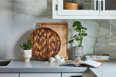 two wooden cutting boards leaning against a kitchen counter walll