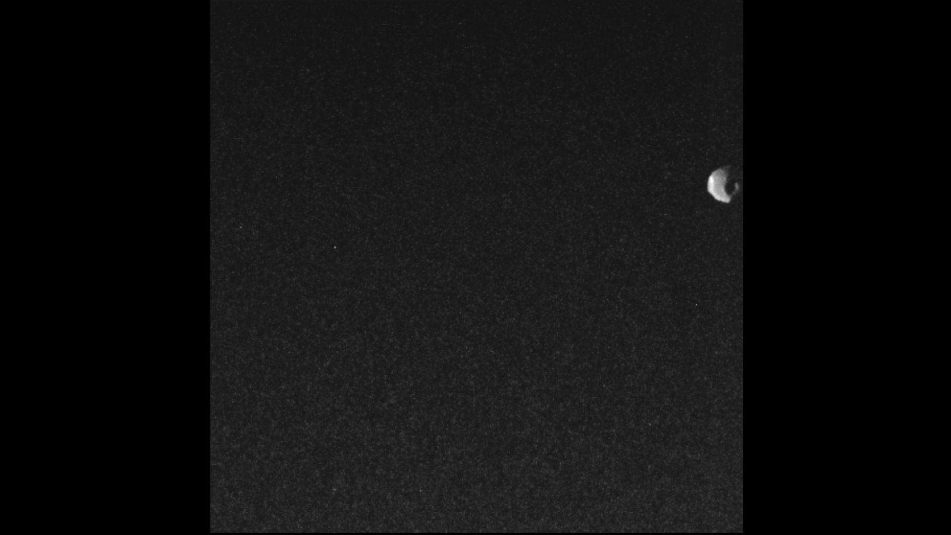 On the upper righthand side of this image of the black of space is a small rock that is actually Jupiter's Moon Thebe.