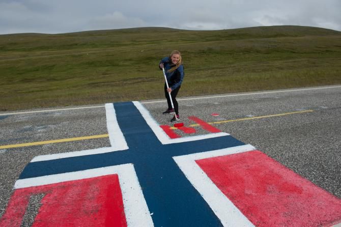 A fan paints the Norwegian flag on the road