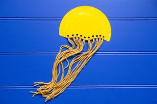 Hole punch the paper plate and add yarn tentacles