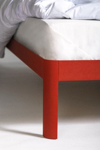 A detail of the bed's leg, in red aluminium and featuring a curved edge