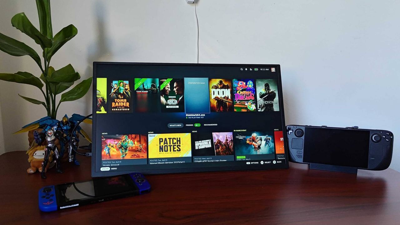 Uperfect Umax portable monitor connected to Steam Deck on woodgrain desk next to plant, Pharah and Samus figures, and Nintendo Switch lying on left hand side.