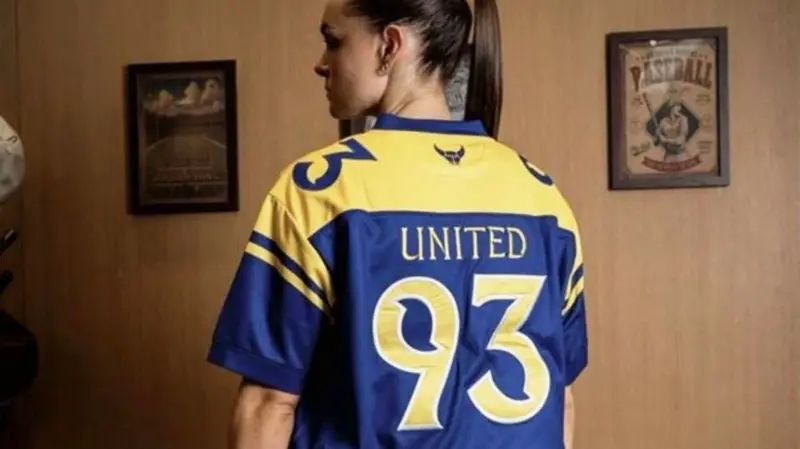 Rear view of a woman wearing a football shirt with 'United 93' written on the back
