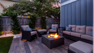 Patio furniture surrounding a lit firepit in a backyard