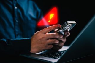 Person with warning notification and spam message icon on mobile phone