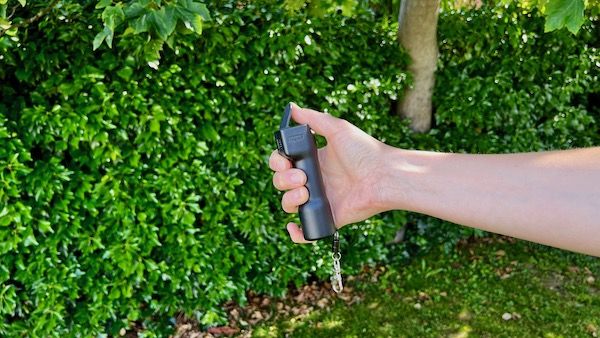 En hand som håller Plegium Smart Försvarsspray.