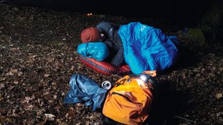 Survival skills and gadgets 101: a man camps out in the wilderness at night and sleeps on a padded camping mat