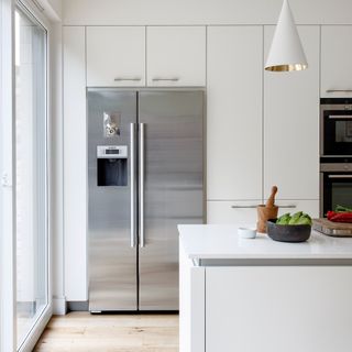 A white minimalist kitchen with a silver fridge