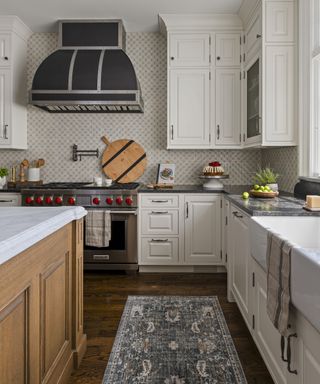 Kitchen with white cabinets, range and hood, wood island, wood floor, and area rug