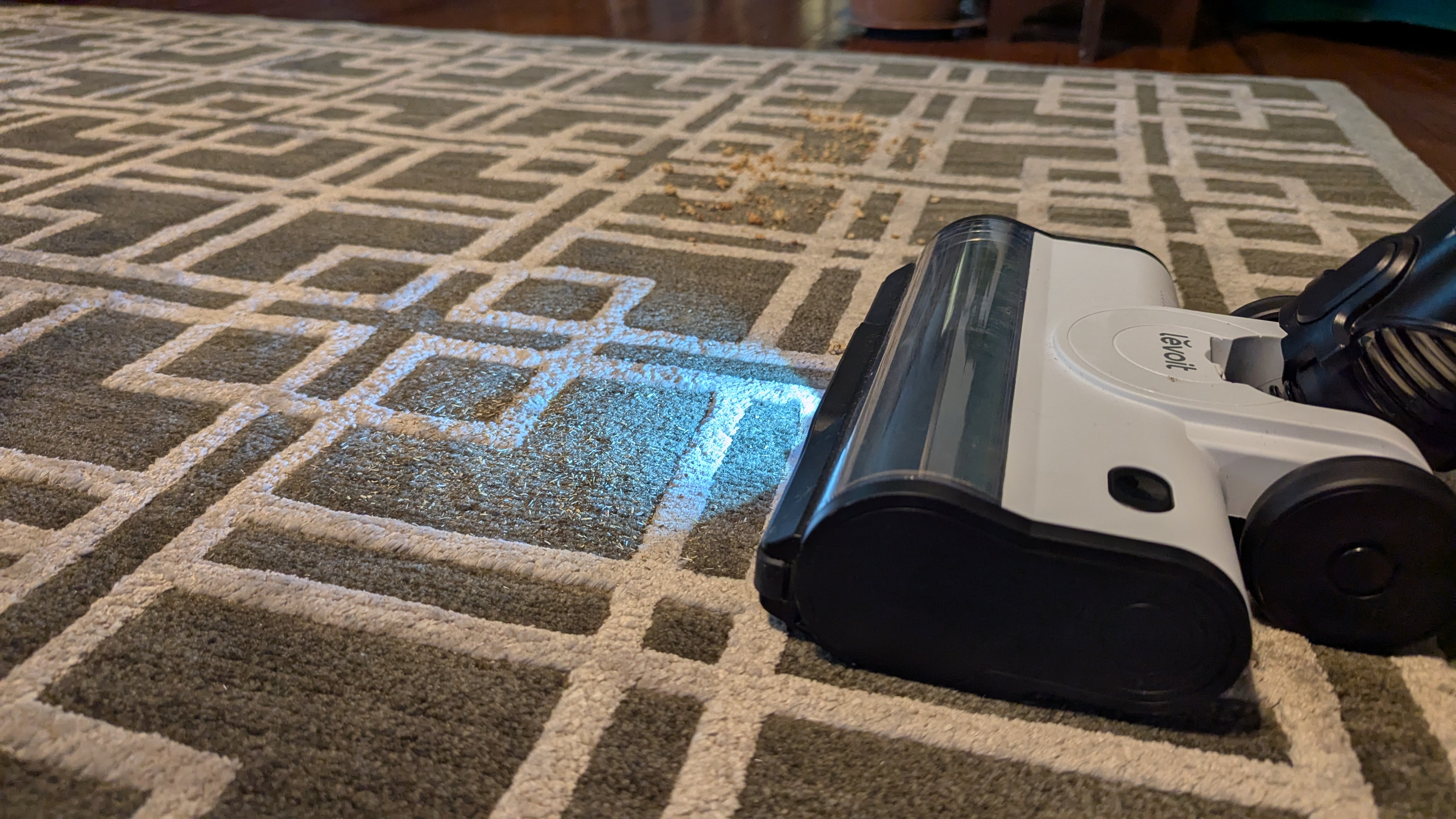 Levoit Aero vacuum being used to clean debris from a patterned rug