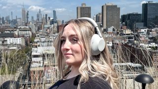 A woman wearing white Sony WH-1000XM6 noise-cancelling headphones
